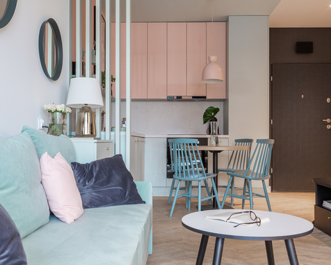 Przytulne studio z miętową sofą, różowym aneksem kuchennym i turkusowymi krzesłami przy stole