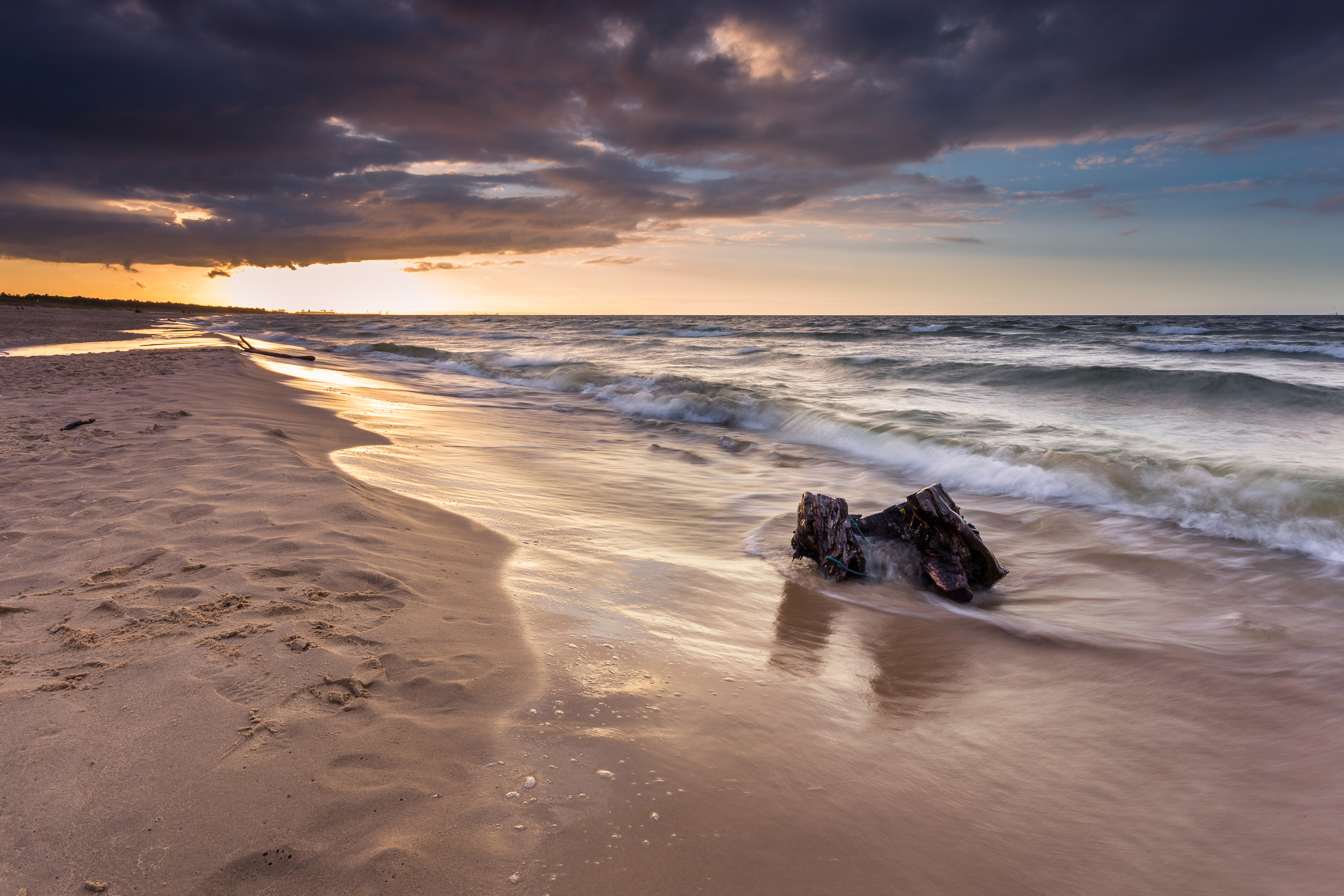Piaszczysta plaża i morskie fale w świetle zachodzącego słońca
