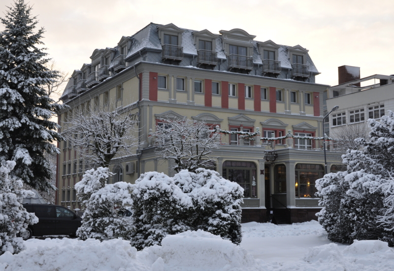 klasyczny butikowy hotel Irys w Świnoujściu z dachem i drzewami pokrytymi śniegiem czarująca zimowa atmosfera, ciepłe światło z dużych okien lobby