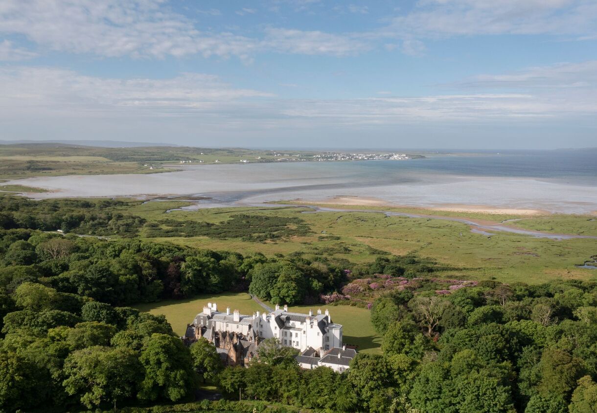 Secluded coastal manor hotel set on lawns and woodland, overlooking tidal estuary, sandy beach and distant seaside village