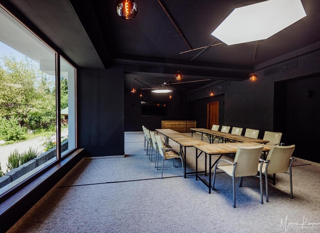 Moderner Konferenzraum mit Holztischen, cremefarbenen Stühlen und großem Fenster mit Blick ins Grüne