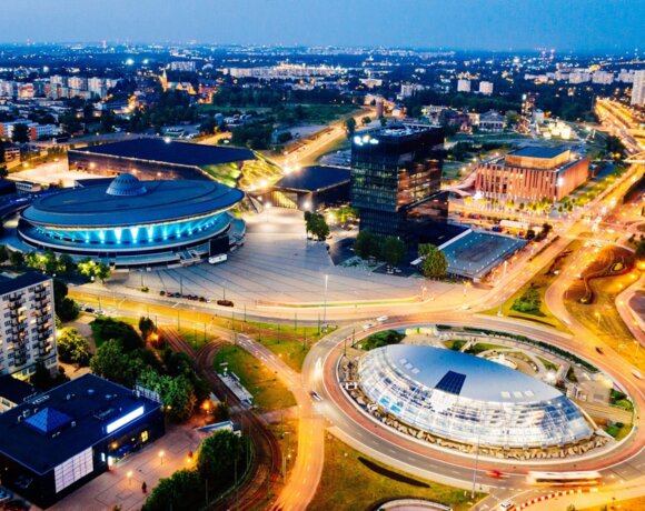 Nighttime view of a modern city with illuminated streets and distinctive oval convention and office buildings