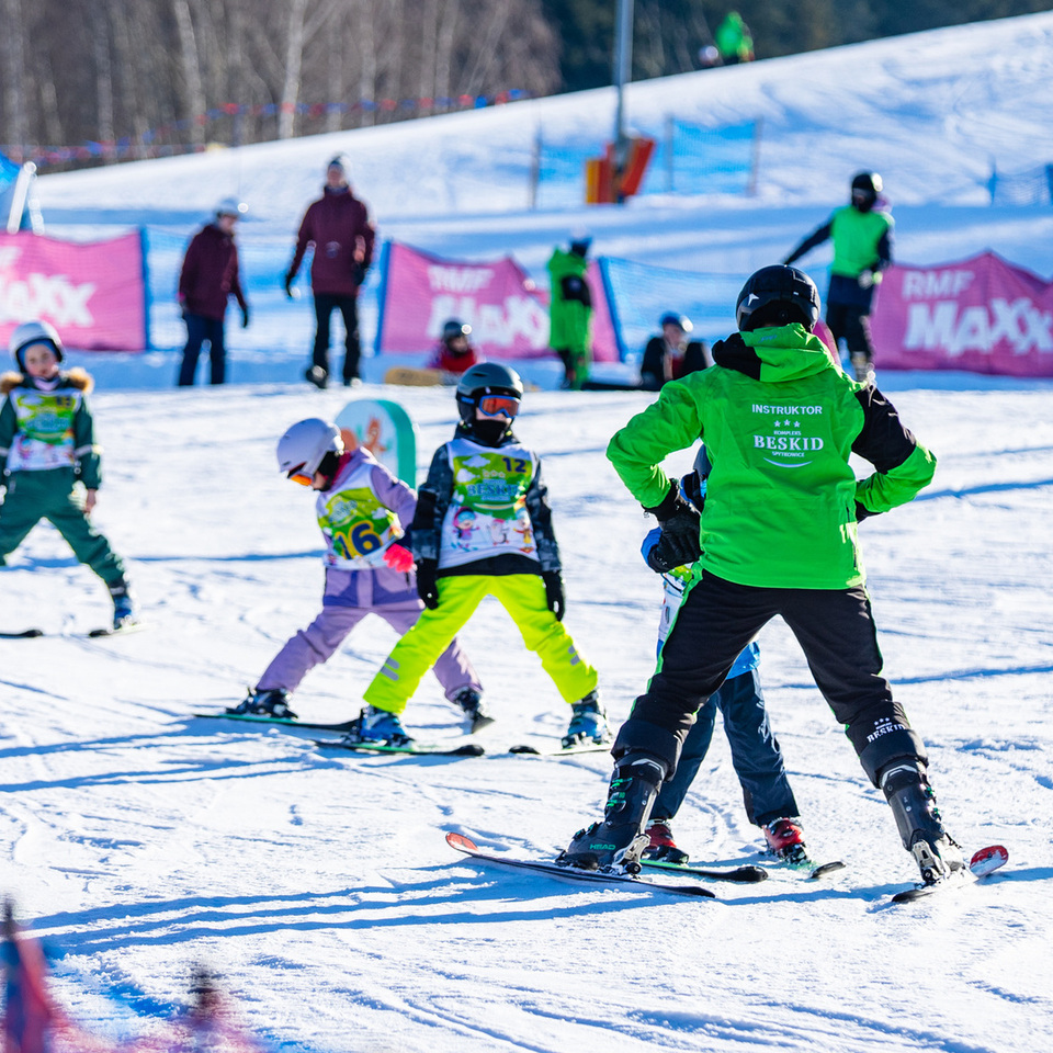 Instruktor narciarstwa uczy dzieci podstaw jazdy na nartach na zaśnieżonym stoku w ośrodku narciarskim Beskid Spytkowice.