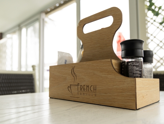 Wooden caddy engraved French Vanilla holding salt and pepper shakers and napkins on a sunlit dining table