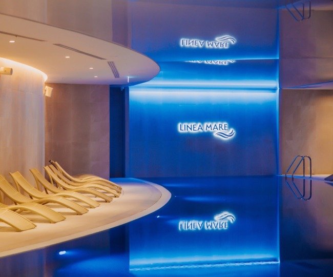 A wellness area with sun loungers at Aqua Mare and an indoor pool in the shape of a sea wave - Linea