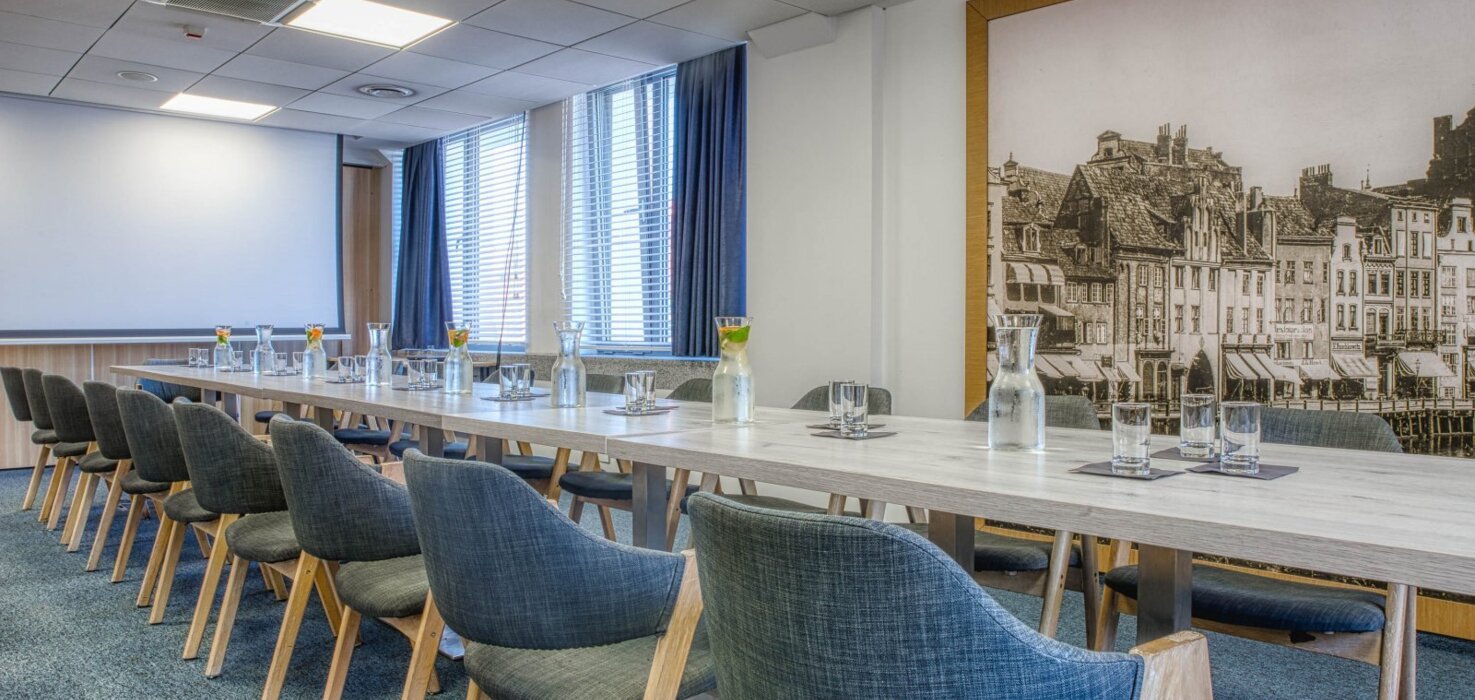 Sala konferencyjna z widokiem na marinę jachtową i niebieskimi krzesłami.