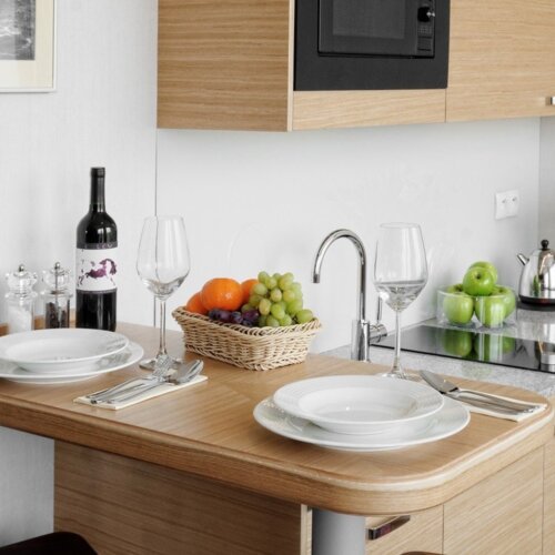 Aneks kuchenny w apartamencie hotelowym ze stołem i krzesłami.