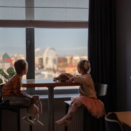 Dwoje dzieci siedzi przy stole w pokoju hotelowym w Gdańsku.