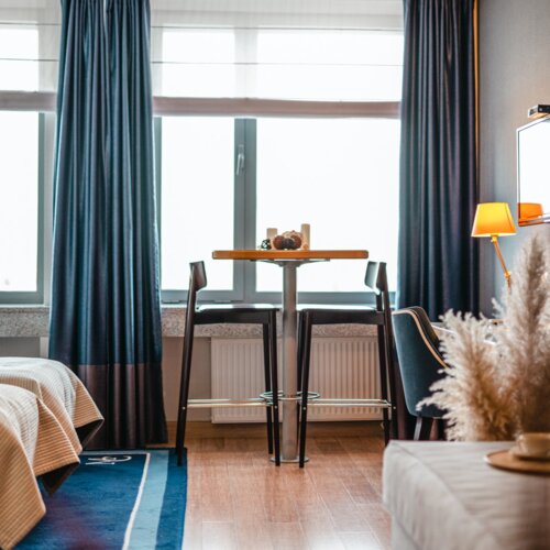 Pokój hotelowy w Gdańsku z dwoma łóżkami i stolikiem barowym.