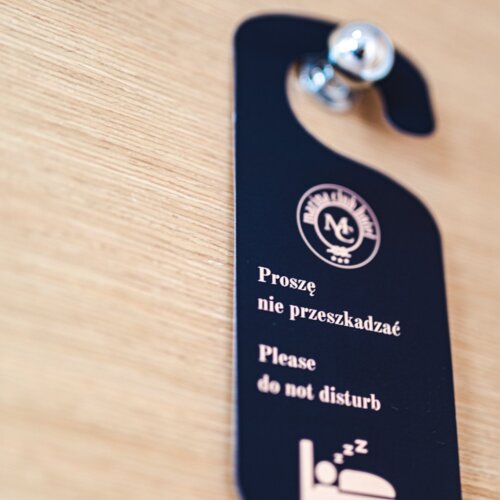 Granatowa zawieszka hotelowa na drzwi z logiem hotelu i napisem 