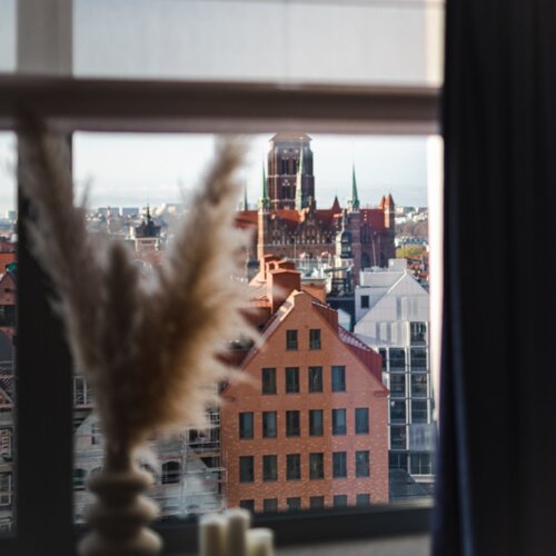 Trawa pampasowa stojąca w wazonie na parapecie okna ze Starym Miastem w Gdańsku w tle.