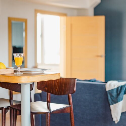 Szklanka z sokiem pomarańczowym i dwa krzesła przy stoliku barowym.