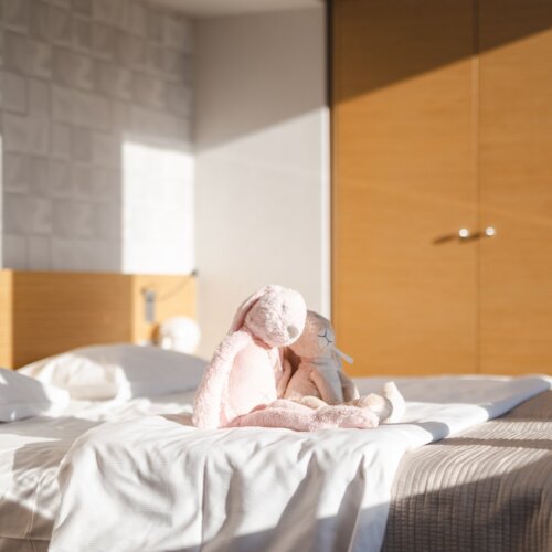 Promienie słońca padające na dwa pluszowe króliczki siedzące na łóżku.