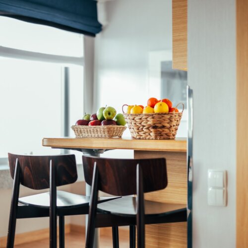 Dwa kosze z owocami na wyspie kuchennej z krzesłami.