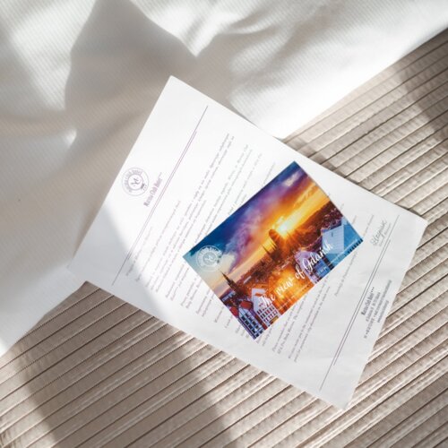 List powitalny i pocztówka leżąca na łóżku hotelowym.