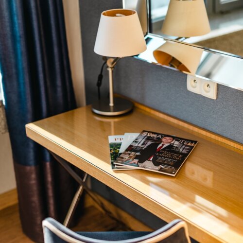 Trzy czasopisma leżące na biurku hotelowym.