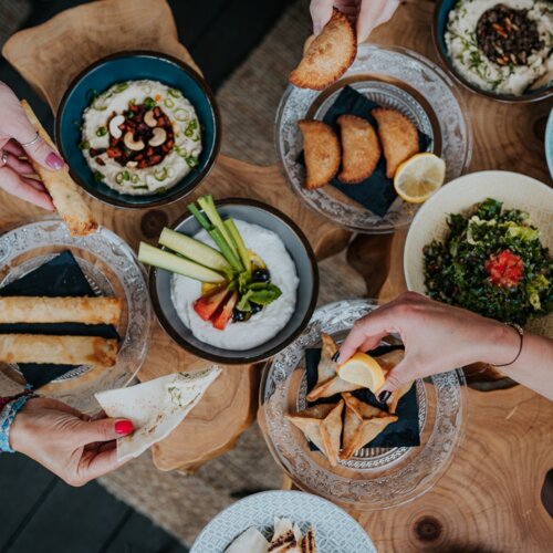 Sechs Teller mit orientalischen Gerichten auf einem Holztisch.