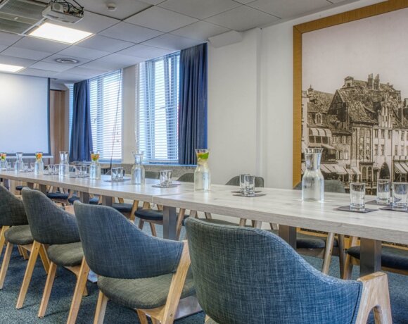 Sala konferencyjna z widokiem na marinę jachtową i niebieskimi krzesłami.