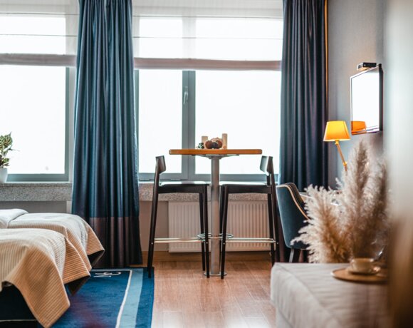 Pokój hotelowy w Gdańsku z dwoma łóżkami i stolikiem barowym.