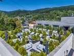 Rooftop hotel terrace with cushioned loungers, potted evergreens, umbrellas and mountain village view with cable car.