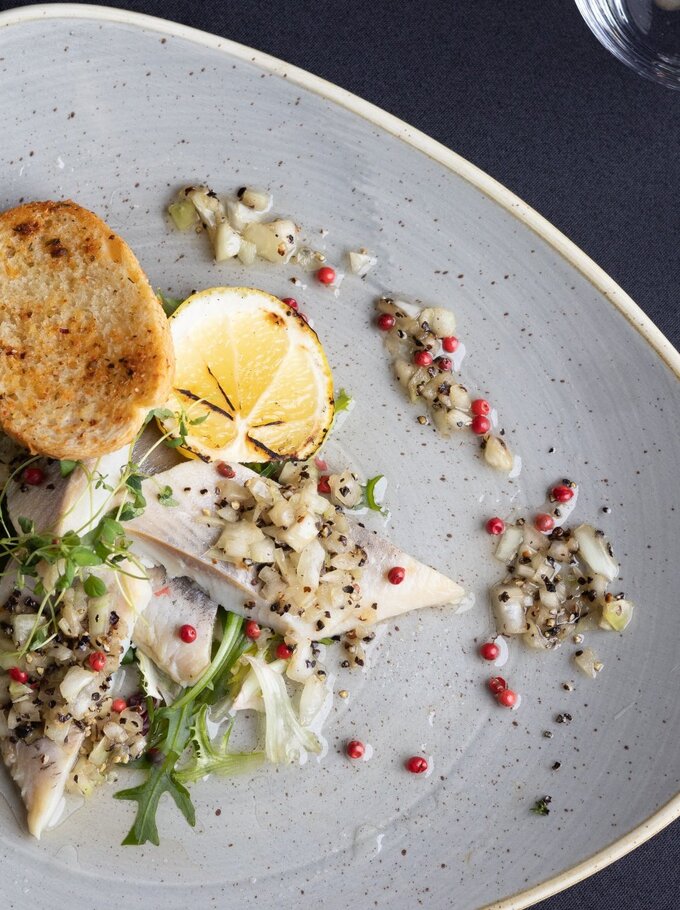 Vorspeise im Restaurant: geräucherte Fischfilets mit fein gehackter Zwiebel, Sprossen, gegrillter Zitrone und Crostini