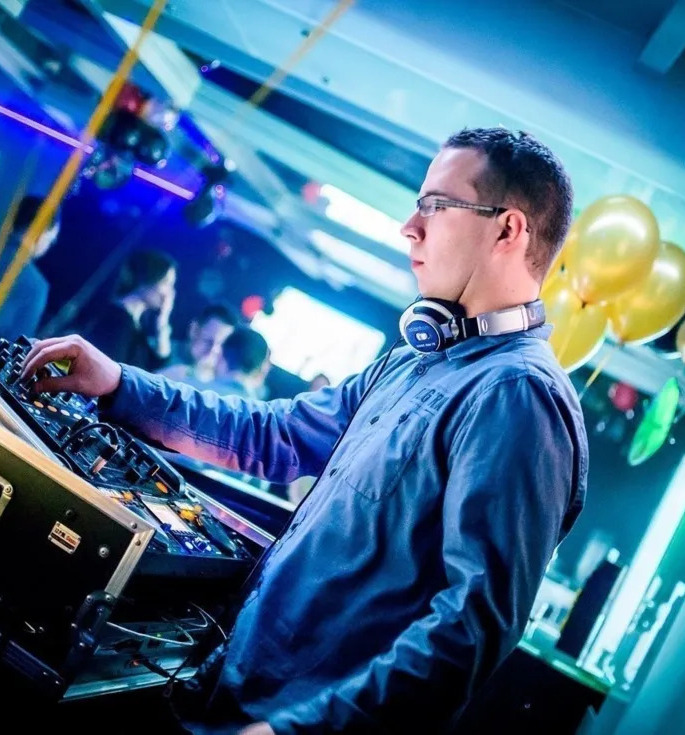 Live DJ mixing at a hotel lounge with headphones, illuminated console, balloons and colorful party lighting