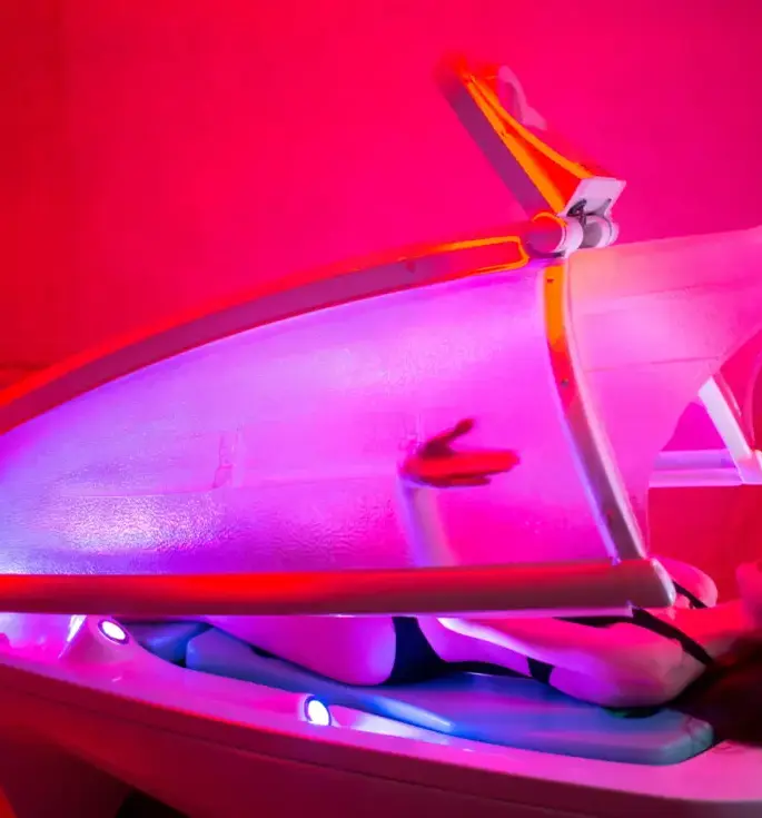 Stimmungsbeleuchtete Spa-Kapsel mit Farbtherapie-LEDs, Gast im Badeanzug liegt entspannt in einer Wellness-Kabine.