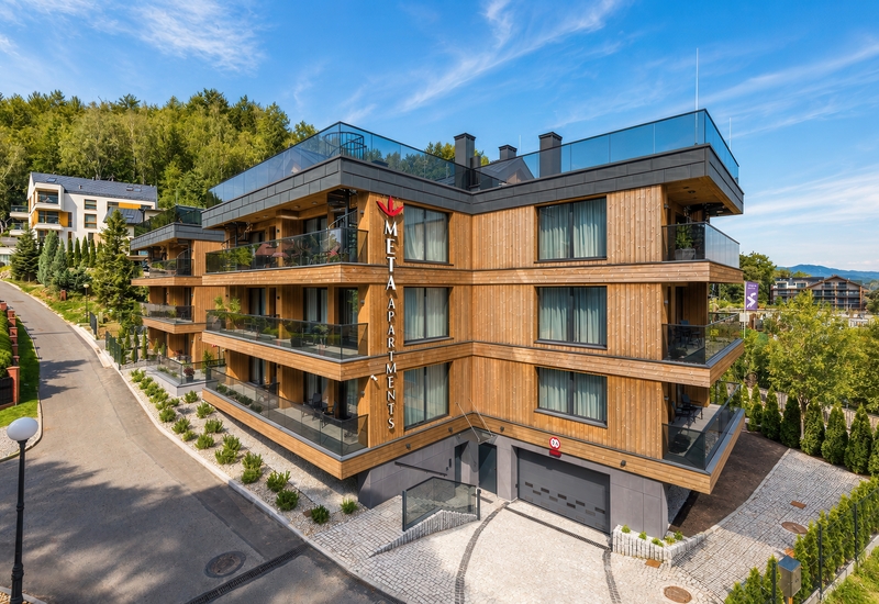 Modern wooden apartment hotel with glass balconies, rooftop terrace, private parking and forested hillside views