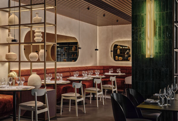 Elegantní restaurace s vínovými pohovkami, bílými židlemi a ozdobnou keramikou v moderním a útulném prostředí.