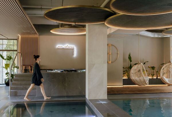 Relaxační spa zóna s moderním bazénem, závěsnými proutěnými křesly a měkkým osvětlením v neutrálních barvách.