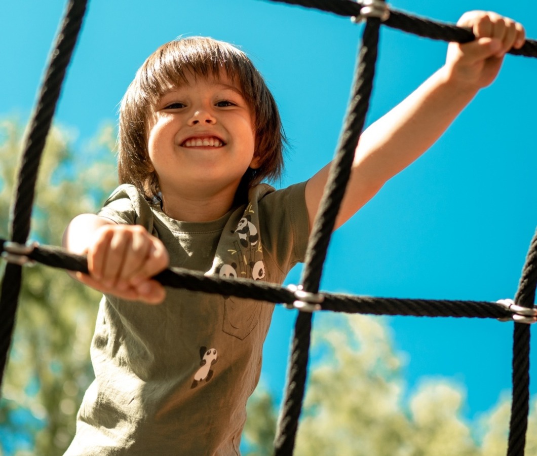 Chłopiec wspinający się na ściance z sznurka na placu zabaw – aktywna zabawa i rozwijanie sprawności