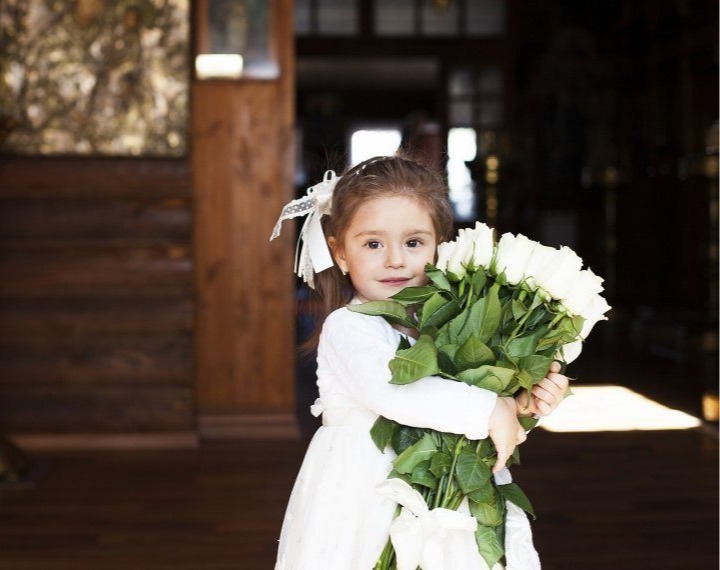Dziewczynka podczas uroczystości trzymająca bukiet białych róż