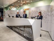 Troje recepcjonistów stojących za dużą, białą recepcją