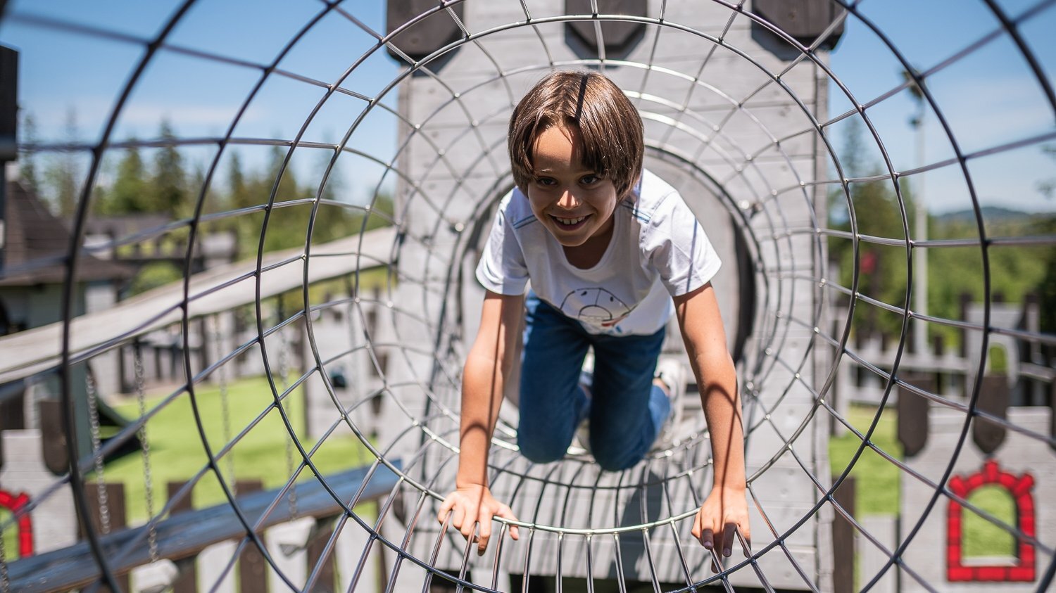 Zadowolony chłopiec na zewnętrznym placu zabaw w Nosalowym Dworze w Zakopanem.