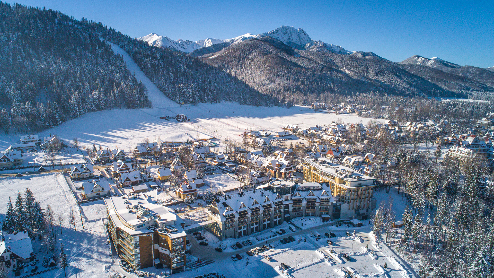 Winter hotel complex in Zakopane seen from above with snow-covered Tatra Mountains in the background