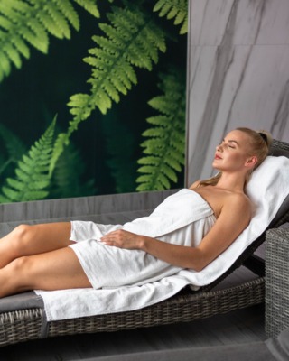 Kobieta leżąca na wygodnym leżaku i odpoczywająca w strefie wellness hotelu