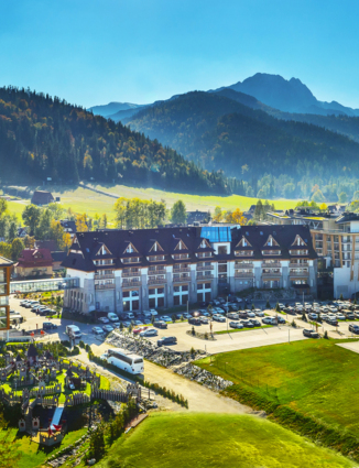 The Nosalowy Dwór hotel complex surrounded by greenery with a view of the mountains in Zakopane