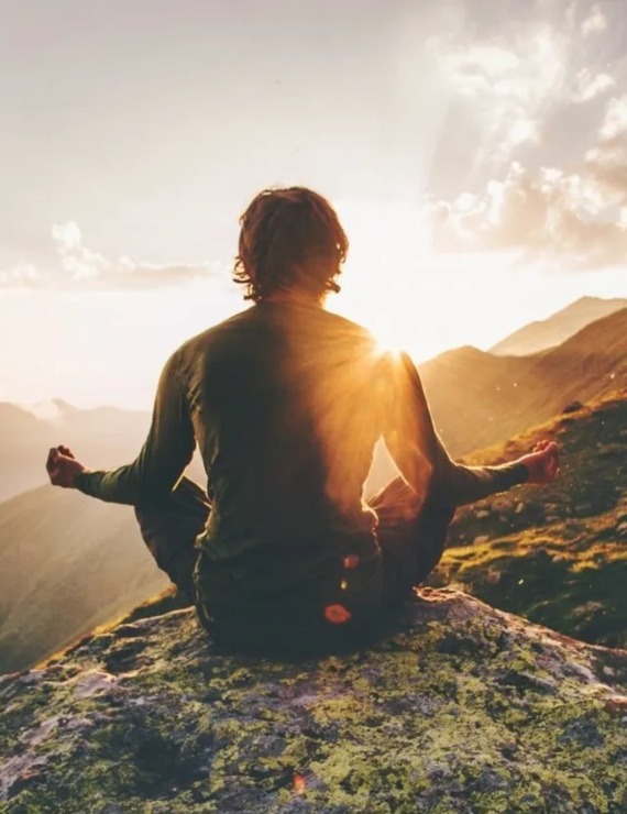 A moment of meditation for a man at sunset with a view of mountain peaks