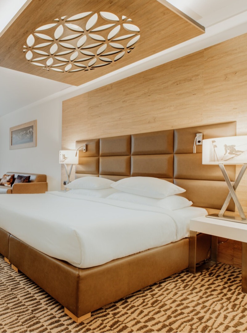 A spacious hotel room in Zakopane style with a large bed and a view through panoramic windows