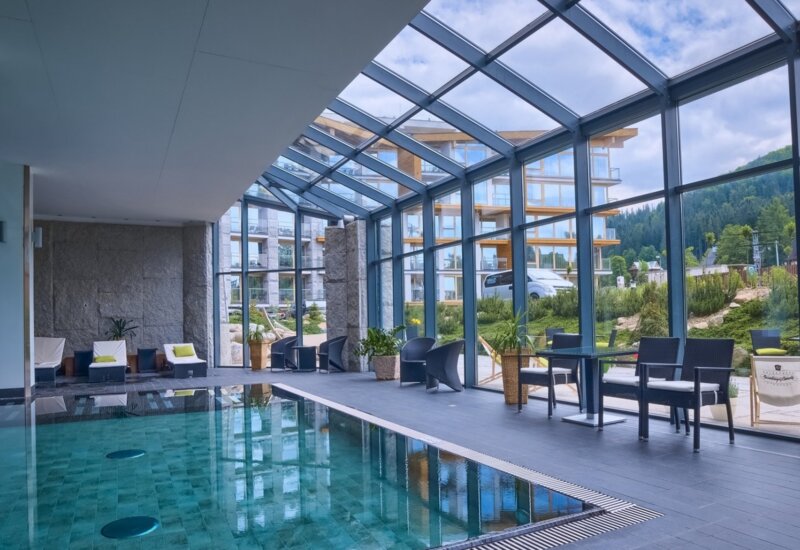 Hotelový bazén s výhľadom na záhradu obklopujúcu objekt