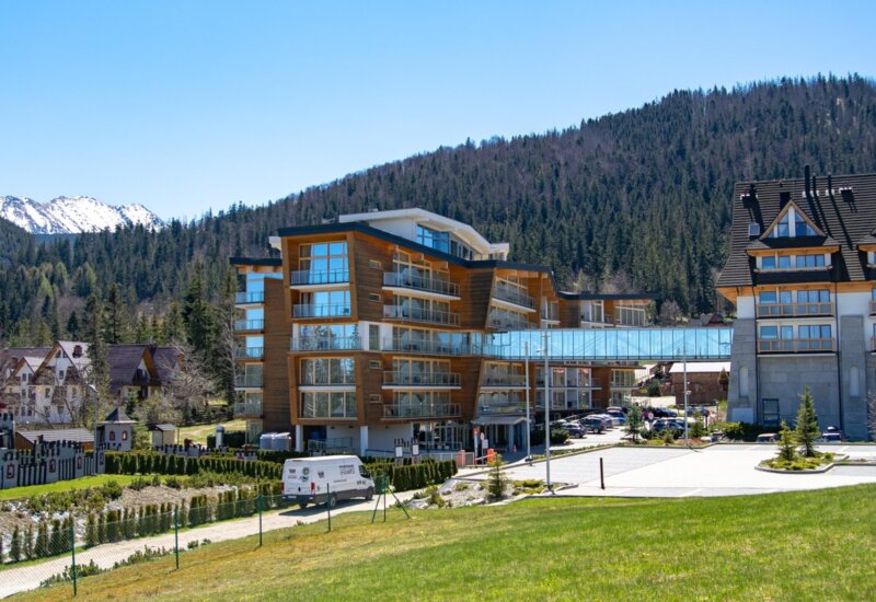 Výhled na horské stredisko s panorámou Tatier v pozadí za slnečného počasia