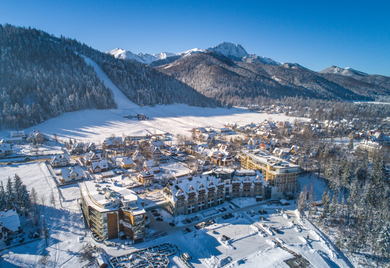Zimowy kompleks hotelowy w Zakopanem widziany z góry, z ośnieżonymi Tatrami w tle
