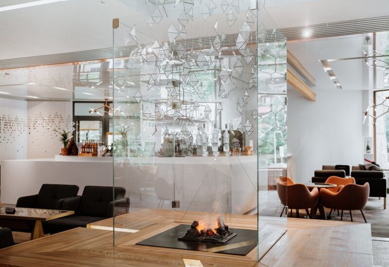 Moderná vstupná hala v svetlých farbách s pohodlnými pohovkami a krbom v presklenej konštrukcii