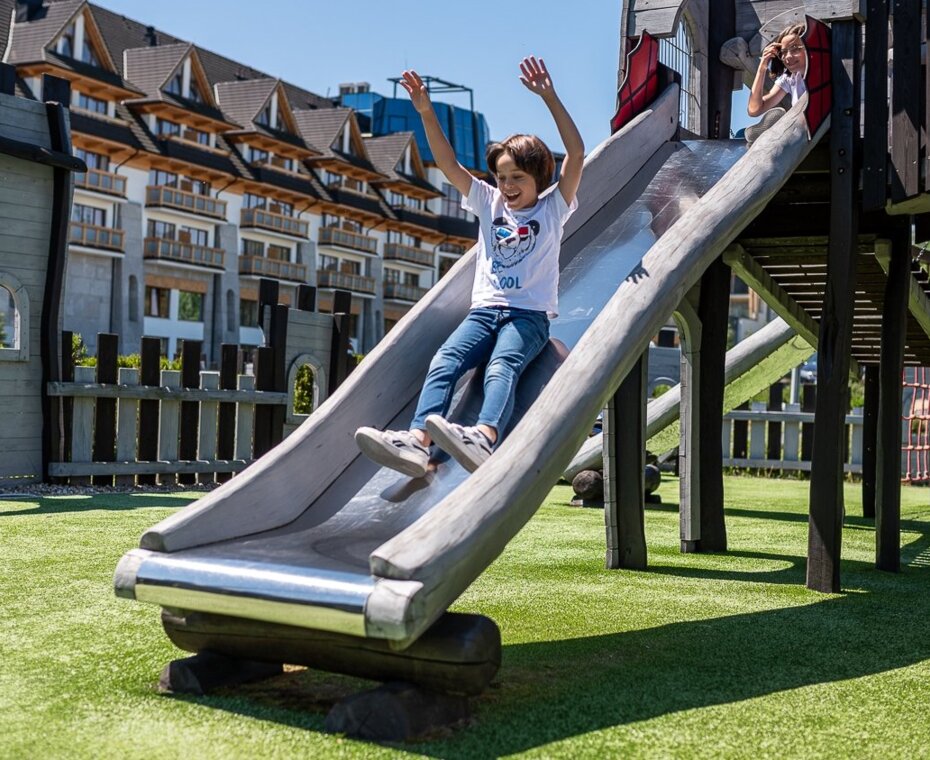 Dziecko bawiące się na placu zabaw Nosalowy Dwór – zjeżdża beztrosko na zjeżdżalni