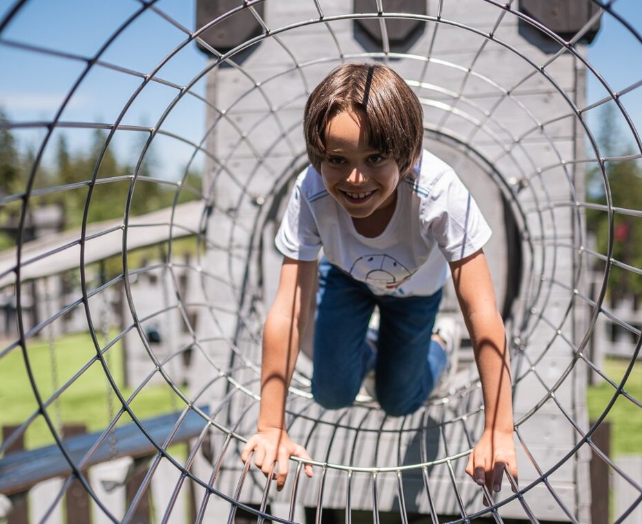 Zadowolony chłopiec na zewnętrznym placu zabaw w Nosalowym Dworze w Zakopanem.