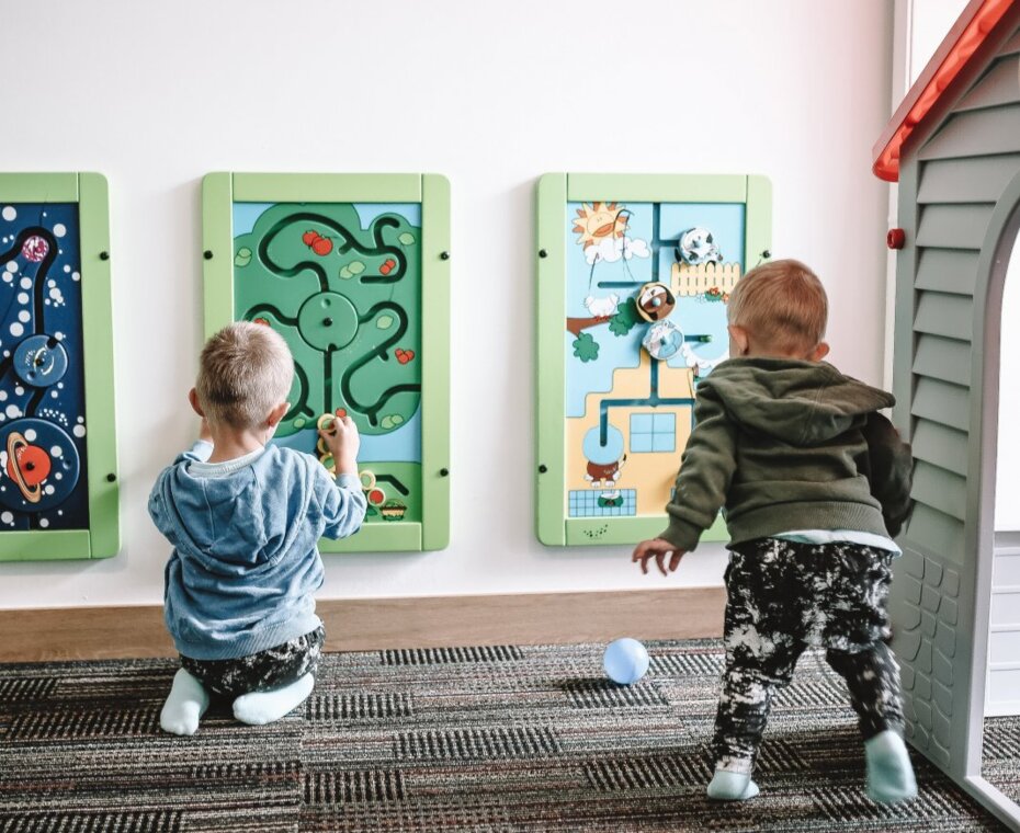 Dzieci bawiące się tablicami sensorycznymi rozwijającymi zmysły i motorykę