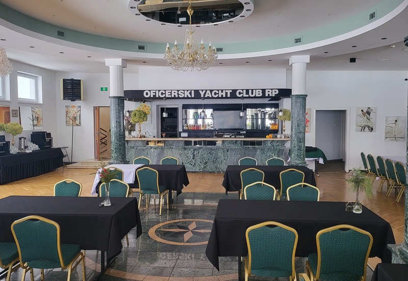 Przestronna sala klubowa z marmurowym barem Oficerski Yacht Club RP, kryształowym żyrandolem, strefą kawową i ustawionymi stołami bankietowymi