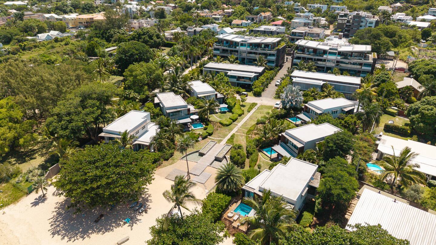 Beachfront boutique resort with modern private villas, palm-lined paths, individual plunge pools and a sandy beach with shaded boardwalk access