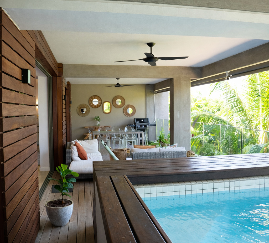 Covered terrace with private plunge pool, wooden deck, cushioned sofa and dining area, ceiling fans and tropical palm views