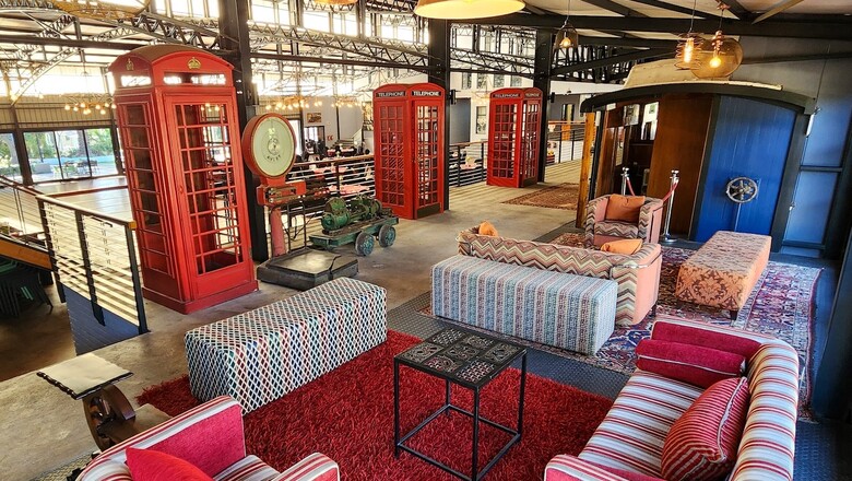 Industrial-style lounge at Safari Hotel & Convention Centre in Rustenburg, featuring patterned sofas, red phone booths, antique décor, layered rugs and warm pendant lighting.